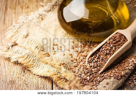 flax seeds and linseed oil in a glass jug on a wooden table, healthy diet with omega 3 fatty acids