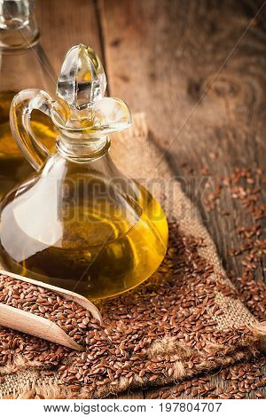 flax seeds and linseed oil in a glass jug on a wooden table, healthy diet with omega 3 fatty acids