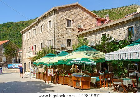 PETROVAC MONTENEGRO - SEPTEMBER 19 2015: Unknown people are resting in cafe-pizzeria Paradiso on waterfront of popular resort town of Petrovac Montenegro