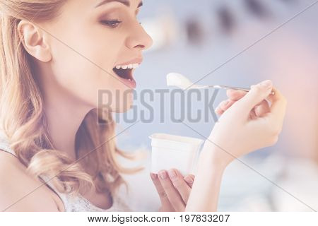 So tasty. Pleasant delighted beautiful woman eating joghurt and maintaining diet while resting at home