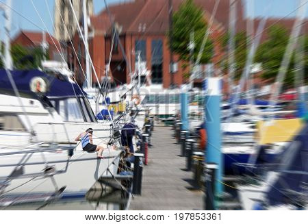 Woman sits on yacht in marina. Zoom effect applied