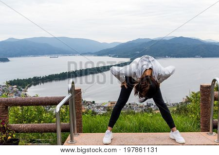Woman looking though the landscape upside down in Amanohashidate in Kyoto