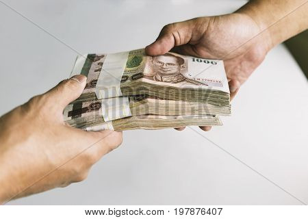 Shot of handover money stack with white table at the back Selective focused.