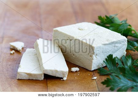 Single Block Of White Tofu With Two Tofu Slices, Crumbs And Fresh Parsley  On Wooden Chopping Board.