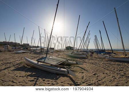 group of catamaran boats in the sun on the beach Els Terrers in Benicassim Castellon Valencia Spain Europe. Blue clear sky and Mediterranean Sea