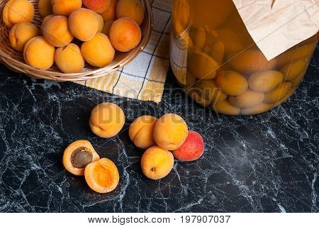 Fresh Organic Harvested Apricots In Basket And Big Glass Jar With Canned Apricot Compote On Dark Mar