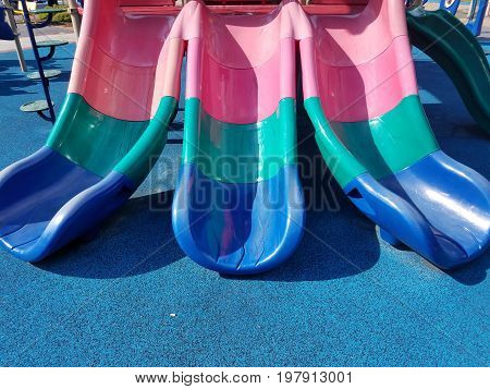multicolored plastic slides on playground with blue ground