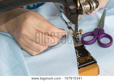 seamstress female sews clothes and put thread in needle. Workplace of tailor. people needlework and tailoring concept - tailor woman threading needle of sewing machine