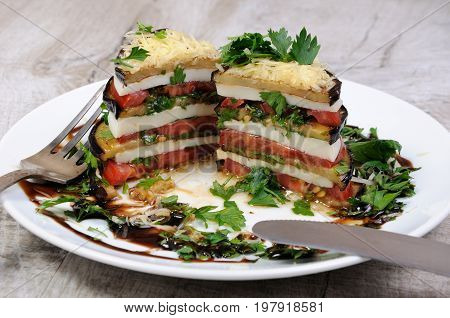 Appetizer from eggplant slices of mozzarella combined in a pile with tomatoes spilled with herbs seasoned Parmesan cheese. In section
