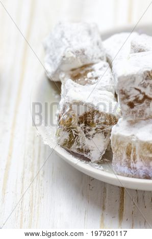 Turkish delight with pistachios on white wooden background.