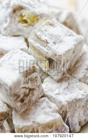 Turkish delight with pistachios on white wooden background.
