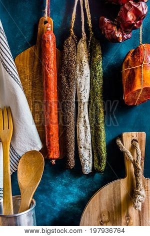 Assortment of traditional Spanish charcuterie meat sausages kitchen utensils towel wood cutting board rustic interior