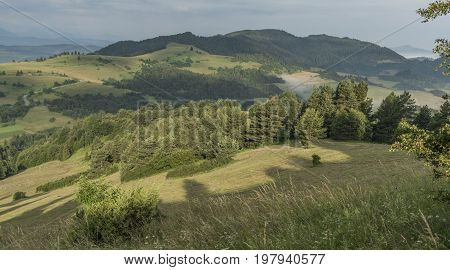 Meadows over Lesnica village in summer cloudy morning