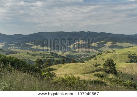 Meadows over Lesnica village in summer cloudy morning