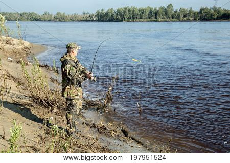 The fisherman catches a pike for spinning off the bank of the channel