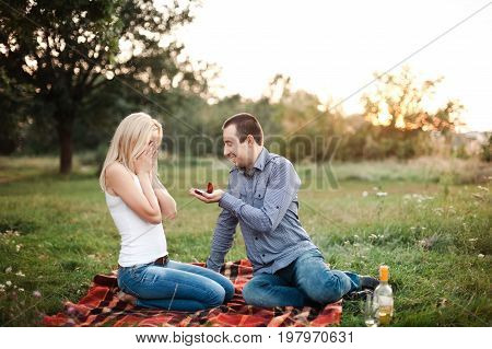 A man proposes to a girl in a park at a picnic