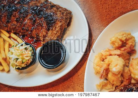 Close up Gourmet Grilled Pork Rib and Fried Potato Wedges on wood Plate with Sauce and Roasted chicken breast and mashed potatoes