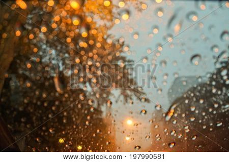 blurred raindrops with street light bokeh on car wind shield in the evening