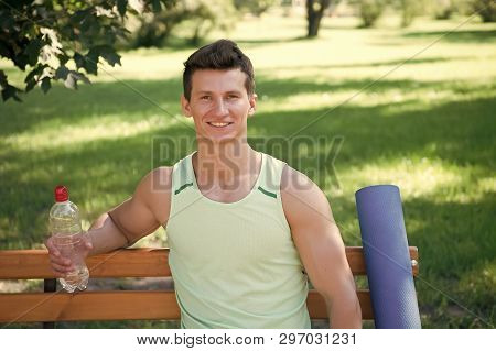 Towards Healthier Lifestyle. Man Smiling Face With Yoga Mat And Water Bottle Sit On Bench In Park. J