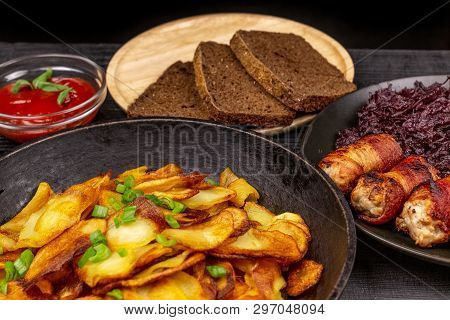 Roasted Potato In The Pot, Pieces Of Rye Black Bread On A Wooden Serving Plate, Homemade Sausages In