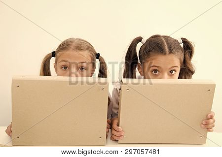 Little Awkward Girls Hide Faces Behind File Folders. Little Awkward Girls Enjoy Playing Together.