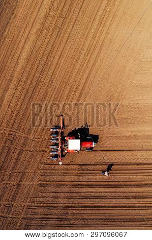Aerial View Of Farmer And Tractor With Crop Seeder Mounted During Corn Planting In Field, Top View