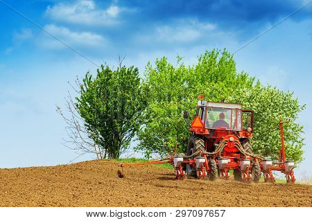 Unrecognizable Farmer Is Driving Tractor With Mounted Crop Seeder And Planting Corn Seed In Field