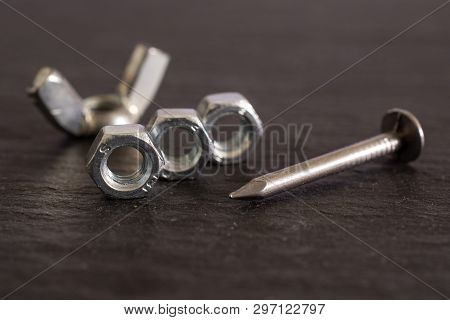 Group Of Five Whole Work Item One Metal Wingnut, Three Locking Nuts And One Nail On Grey Stone