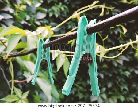 Linen Clothespins In The Yard. Plastic Linen Clothespin On Old Rope On Green Background. Many Multi-