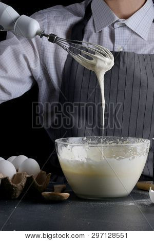 Dough Pouring From The Whisk. Man Manking Pie. Recipe Concept On Dark Background