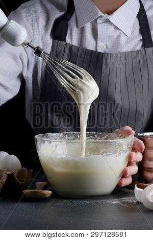 Dough Pouring From The Whisk. Man Manking Pie. Recipe Concept On Dark Background