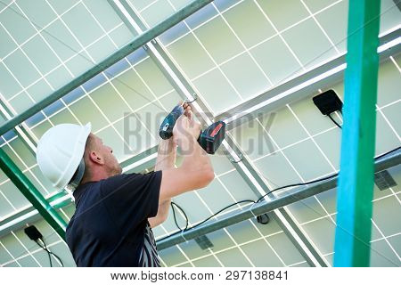 Backview Of Mounter Wearing White Helmet, Uniform Working With Drill Making Holes For Wires In Solar