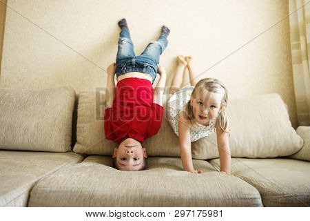 Brother And Sister Playing On The Couch: The Boy Stands Upside Down