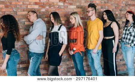 Tired Of Waiting. Millennials Queue. Men Women Standing In Line Leaning Against Brick Wall. Moving F