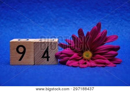 Number Ninety Four With A Purple Daisy On A Blue Background