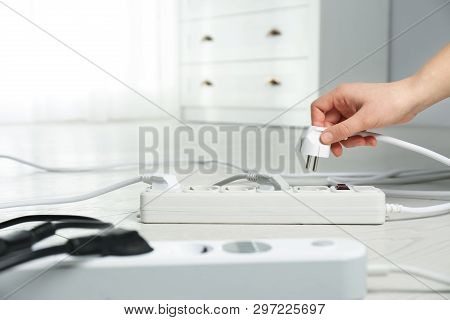 Woman Inserting Power Plug Into Extension Cord On Floor Indoors, Closeup With Space For Text. Electr