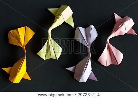 Handmade paper craft origami gold koi carp fishes on black background.Top view, pattern