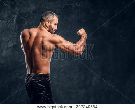 Professional Fighter Showing Kick Fighting Technique. Studio Photo Against A Dark Textured Wall