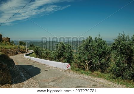 Road With Curves And Stone Guard Rail On Slope In A Countryside Landscape At Evoramonte. A Tiny Fort