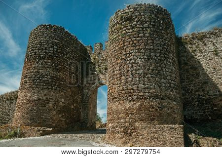 Stone Thick Towers In A Sunny Day Beside The Main Entrance Doorway On The Outer Wall Of Evoramonte. 