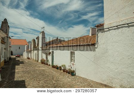 Humble White Wall Houses With Flowers Pots In A Sunny Day, On The Cobblestone Main Street Of Evoramo