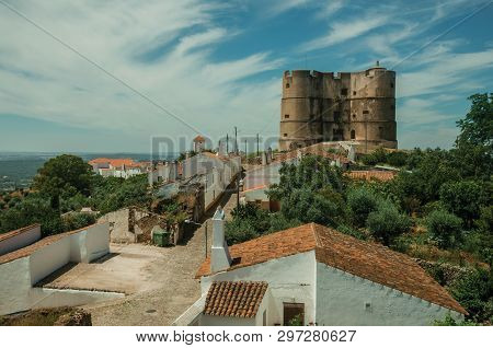 People Walking Up The Main Cobblestone Street In A Sunny Day Towards The Castle Of Evoramonte. A Tin