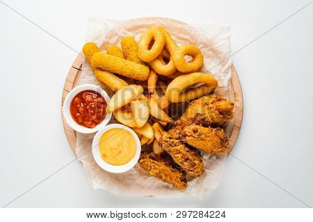 The beer plate with spicy chicken wings, calamari rings, fries onion rings, cheese balls, potatoes, breaded.