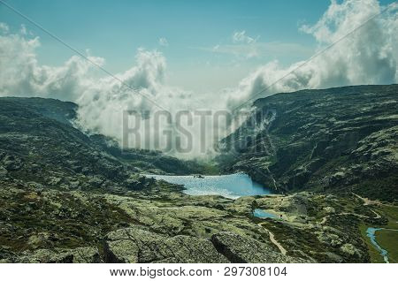 Hilly Landscape Covered By Rocks And Lake, With Clouds Coming From The Ravine On The Highlands At Th