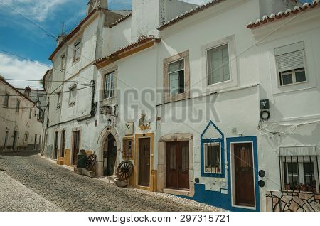 Estremoz, Portugal - July 06, 2018. Old houses with doors on alley with cobblestone pavement in sunny day at Estremoz. A nice little historic town with several marble buildings on eastern Portugal.