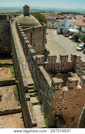 Elvas, Portugal - July 07, 2018. Castle walls with towers in front of cobblestone street and old houses at Elvas. A gracious star-shaped fortress city on the easternmost frontier of Portugal.