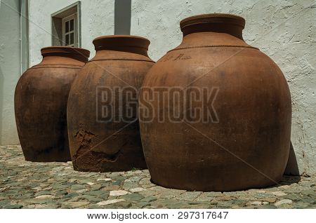 Campo Maior, Portugal - July 8, 2018. Large Earthenware Vessels Over Floor And Rough Plaster Wall At