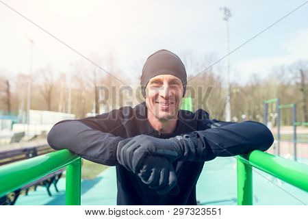Photo of happy athlete pulling up on green horizontal bar