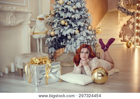 Happy Young Lady With Curlu Hair Gifts By The Fireplace Near The Christmas Tree. New Year Concept.