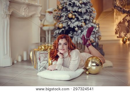 Happy Young Lady With Curlu Hair Gifts By The Fireplace Near The Christmas Tree. New Year Concept.